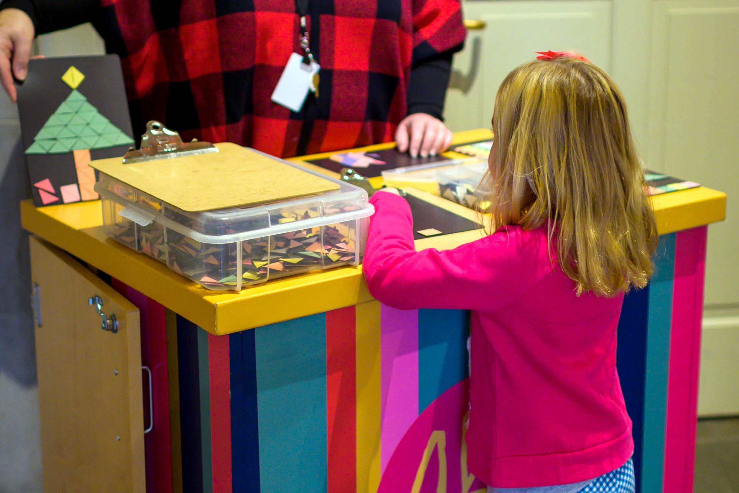 A young girl reaches to grab art materials at an Art Cart