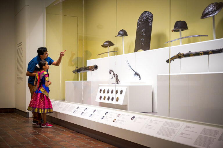 Two visitors viewing a Japanese arms and armor display