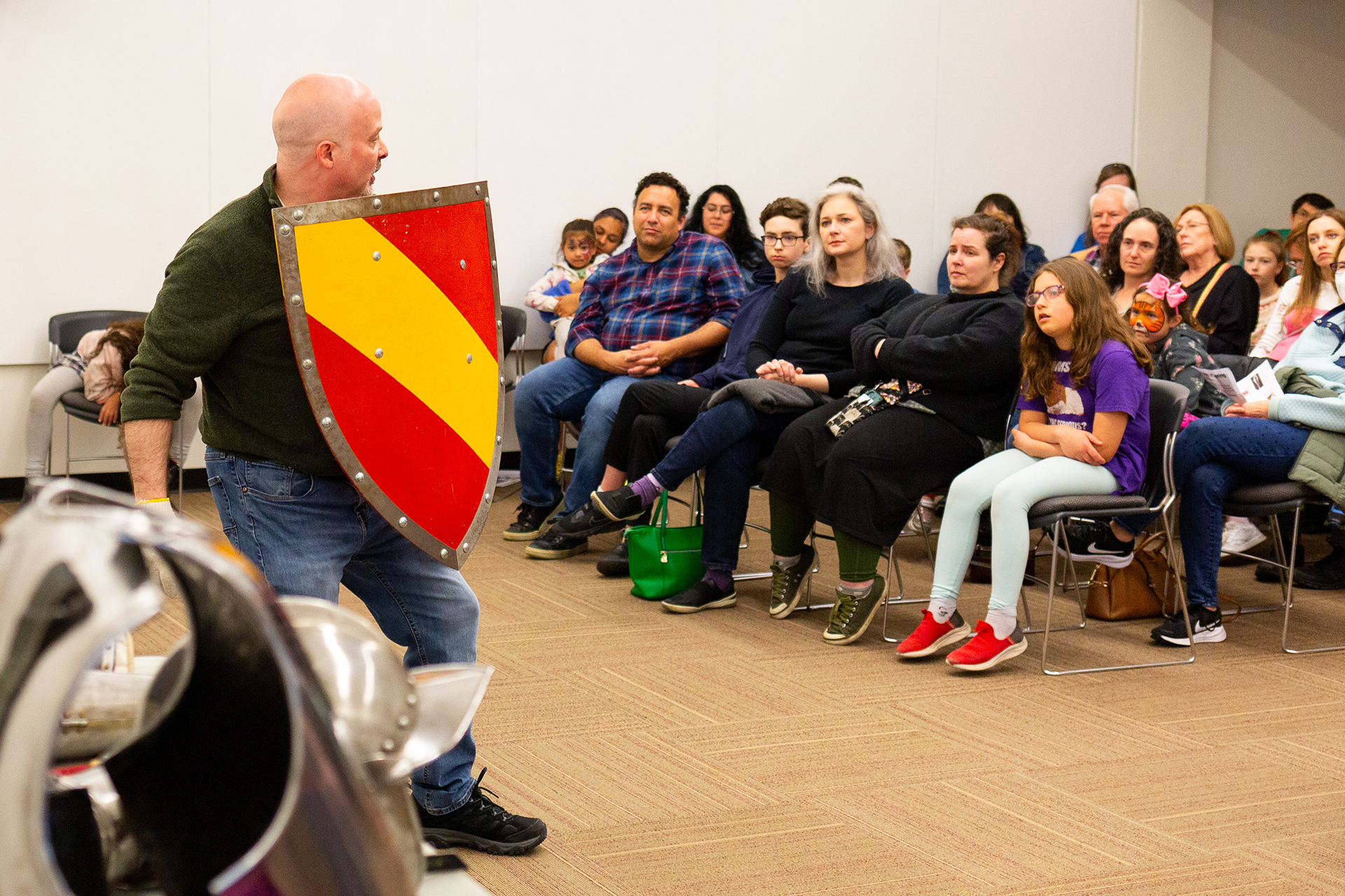 An educator holds up a shield in front of a seated audience
