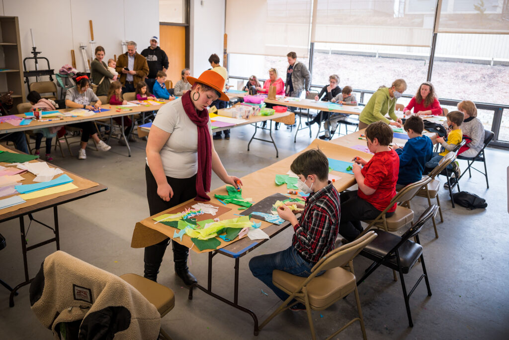 Visitors sitting at desks making art in a studio