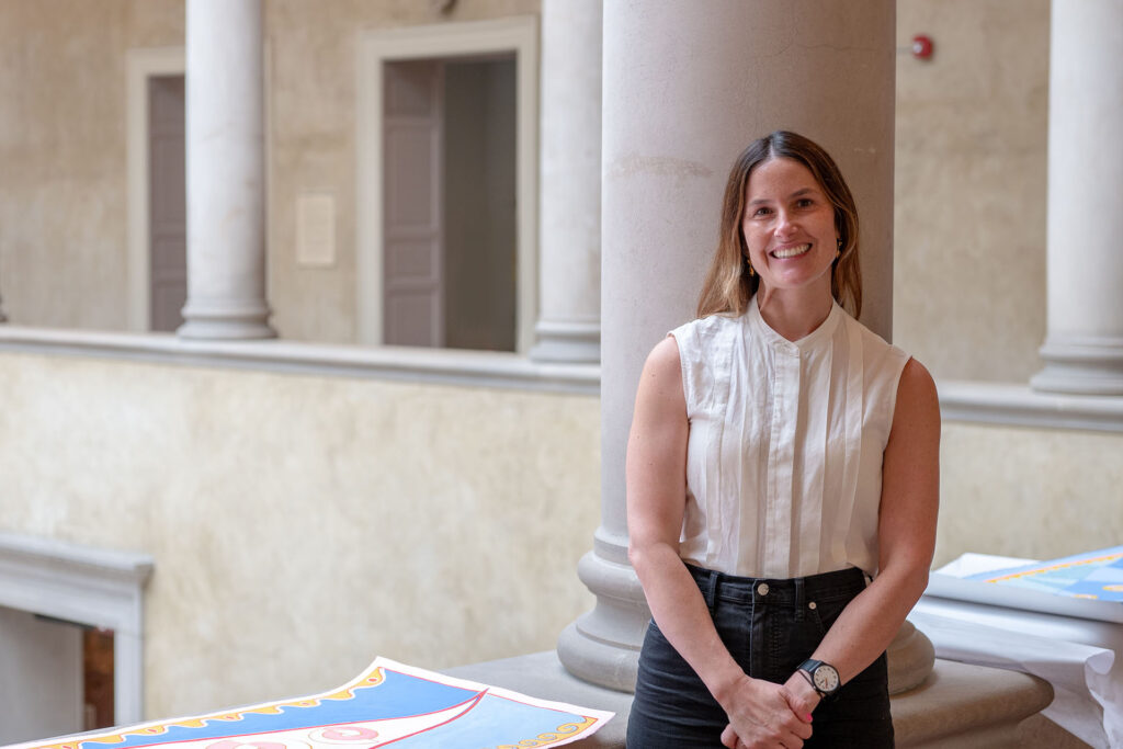 Artist Crystalle Lacouture stands next to concept painting for Wall at WAM