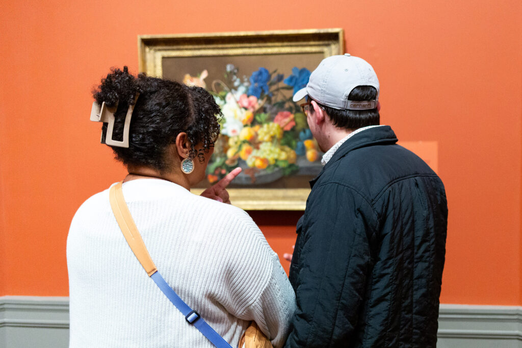 Two guests standing together viewing a painting