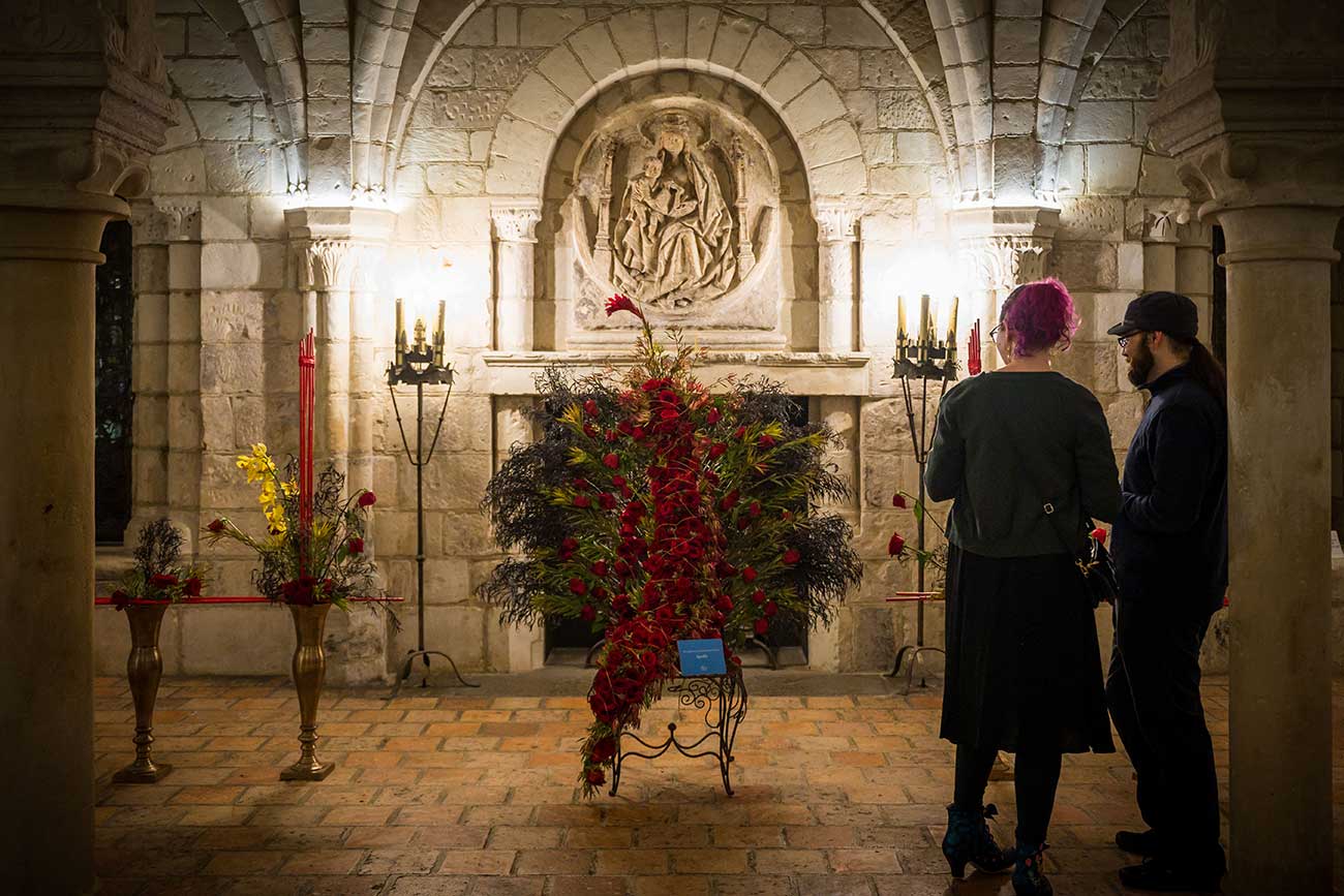 Two visitors viewing floral arrangements on display in the Chapter House